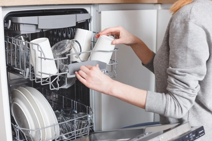 kvinne setter oppvasken i oppvaskmaskinen