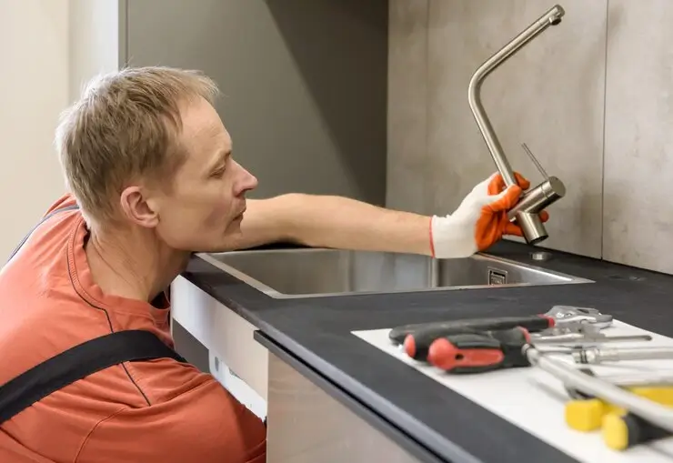 Rørlegger som installerer en kum på kjøkkenvasken