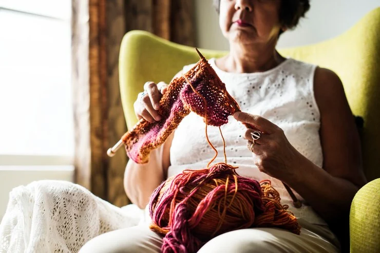 Eldre kvinne med strikkehobby hjemme