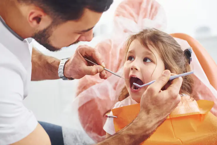 liten jente på besøk hos mannlig tannlege